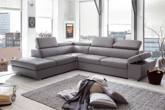 Canapé d’angle design en simili cuir gris clair dans un salon lumineux